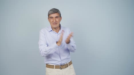 un anciano aplaudiendo emocionado a la cámara.