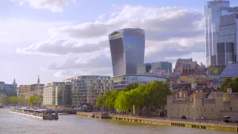 london city skyline and tower of london, landscape view from tower bridge on a sunny summer day with blue sky and light clouds