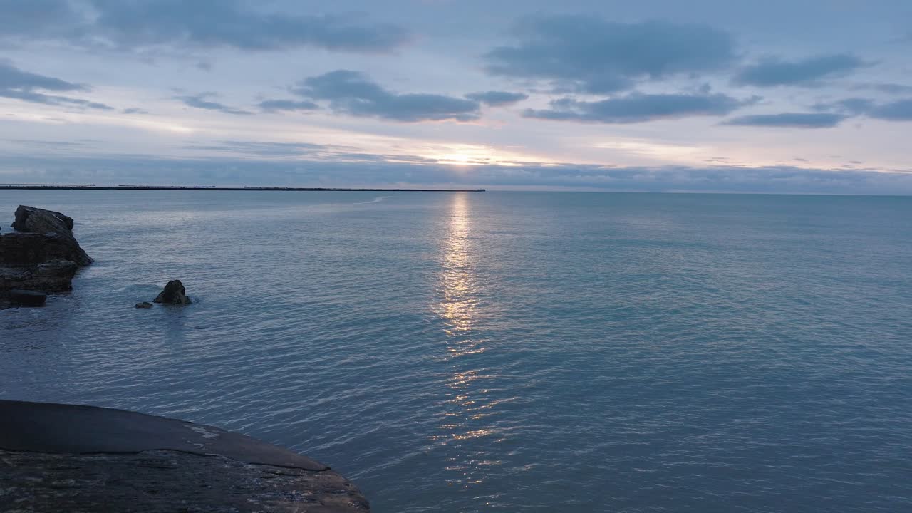 카로스타 콘크리트 해안 요새화 폐허의 아름다운 공중 전망, 잔잔한 발트해의 생생한 고대비 일몰, 겨울 저녁, 넓은 드론 샷이 앞으로 낮게 움직입니다.