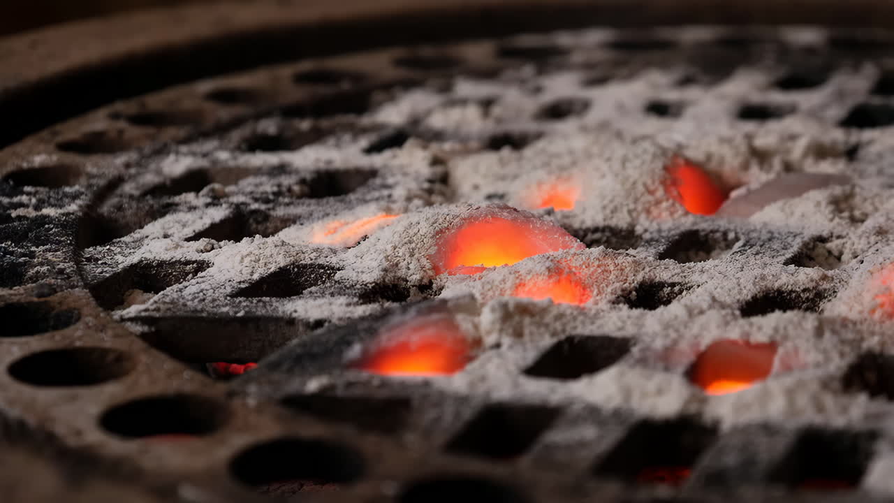 Glowing embers covered in ash on a grill
