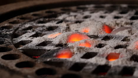 glowing embers covered in ash on a grill