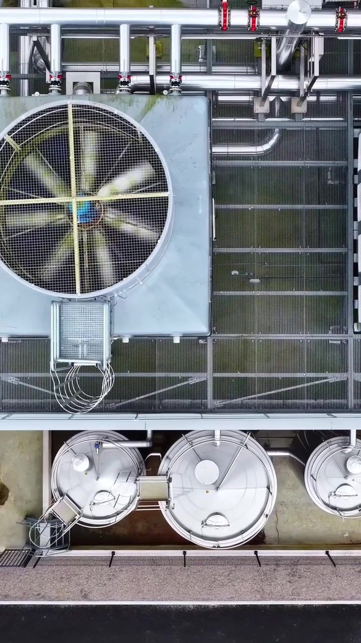 A large industrial cooling system featuring a rotating fan and metal structures. Useful for engineering or industrial process themes.