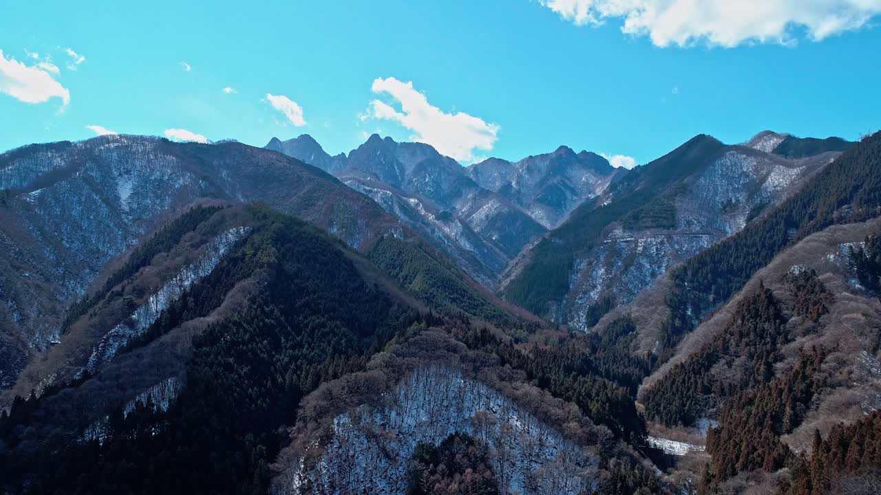 Drone view of snowy Japanese mountains under blue sky