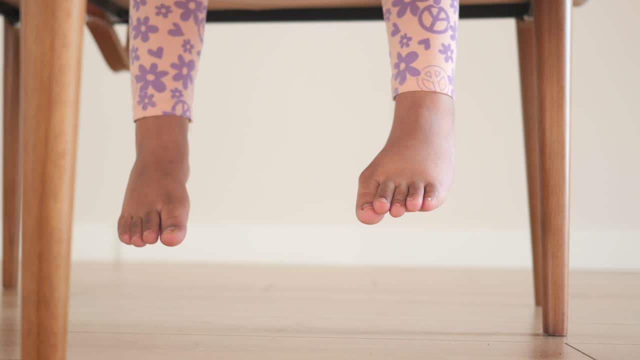 발이 매달린 의자에 앉아 있는 작은 소녀