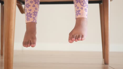 little girl sitting on a chair with feet hanging