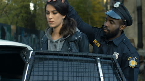 Close-Up-Of-Policeman-Leading-And-Sitting-Pretty-Young-Woman-Villain-In-Police-Car