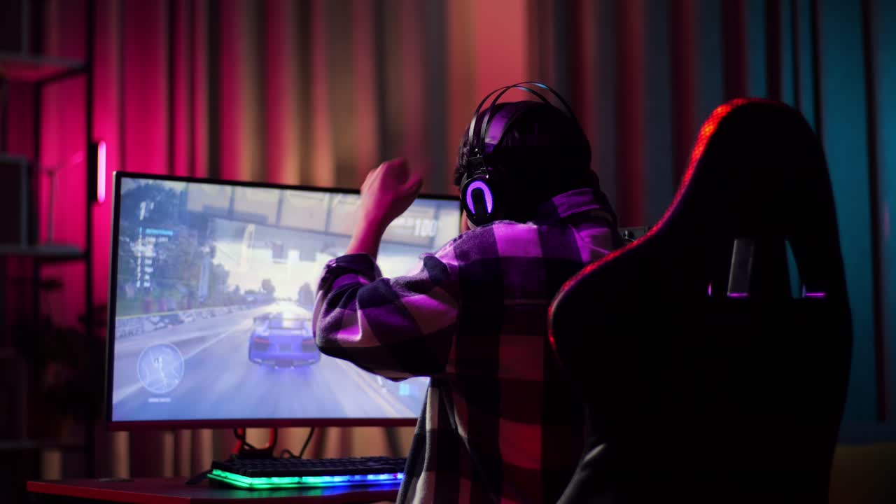 Ragazzo adolescente asiatico gamer entusiasta festeggia la vittoria mentre gioca a un videogioco al computer, un videogioco di corse.