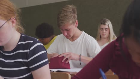 caucasian high school boy looking for a pen in class