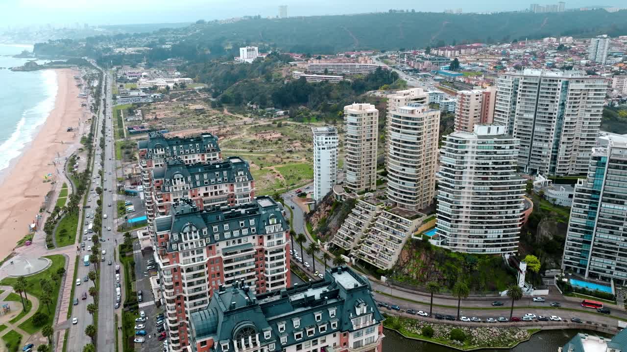 levantamiento aéreo sobre lujosos edificios de apartamentos y resorts cerca de la playa de arena y el mar, tráfico en la avenida, viña del mar, chile