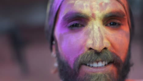 indian man close-up of face smeared with bright holi colors