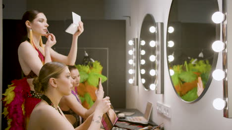 three showgirls applying makeup in the backstage 2