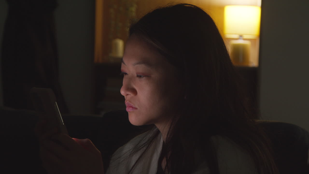 집에서 저녁을 보내고 소파에 앉아 휴대전화를 들고 인터넷이나 소셜 미디어를 스크롤하는 여성의 클로즈업 4