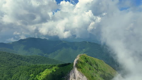 flying trough white fluffy clouds above green mountain peaks