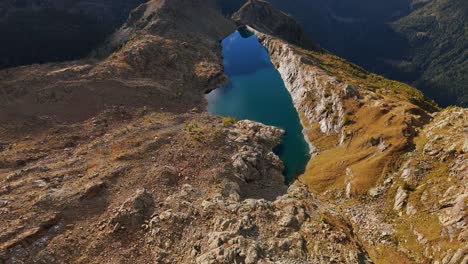 aerial view of lago pirola nestled in the breathtaking valmalenco alps, showcasing a serene lake surrounded by mountainous landscapes.pull back, tilt up shot