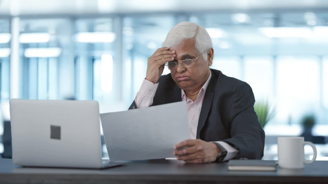 Tensed Indian senior manager reading business reports