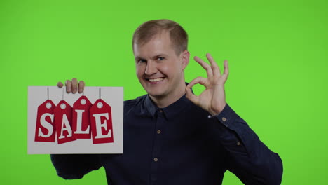 happy man holding sale word inscription and showing ok sign. guy rejoicing with good sale discounts