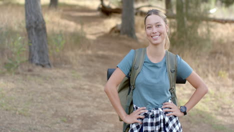 young caucasian woman smiles during a hike in the woods with copy space