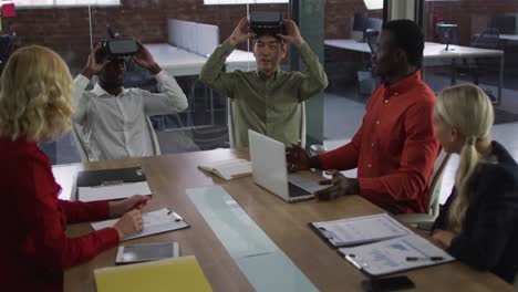 Diverse-group-of-business-colleagues-sitting-in-meeting-room-using-vr-headset-applauding