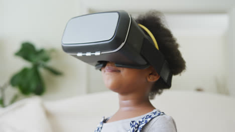 Lächelndes-Afroamerikanisches-Mädchen,-Das-Im-Wohnzimmer-Mit-Einem-VR-Headset-Spielt