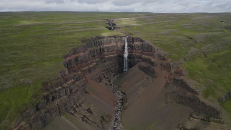 vuelo hacia atrás cinematográfico que muestra la impresionante cascada hengifoss y el paisaje verde de islandia