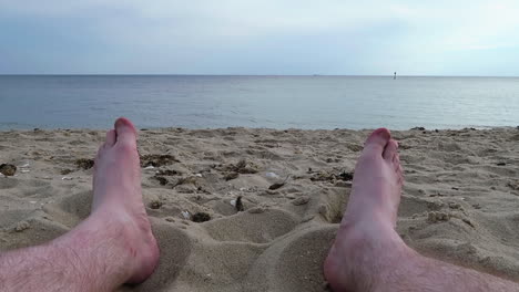 mans feet wiggling on hampton beach, day time