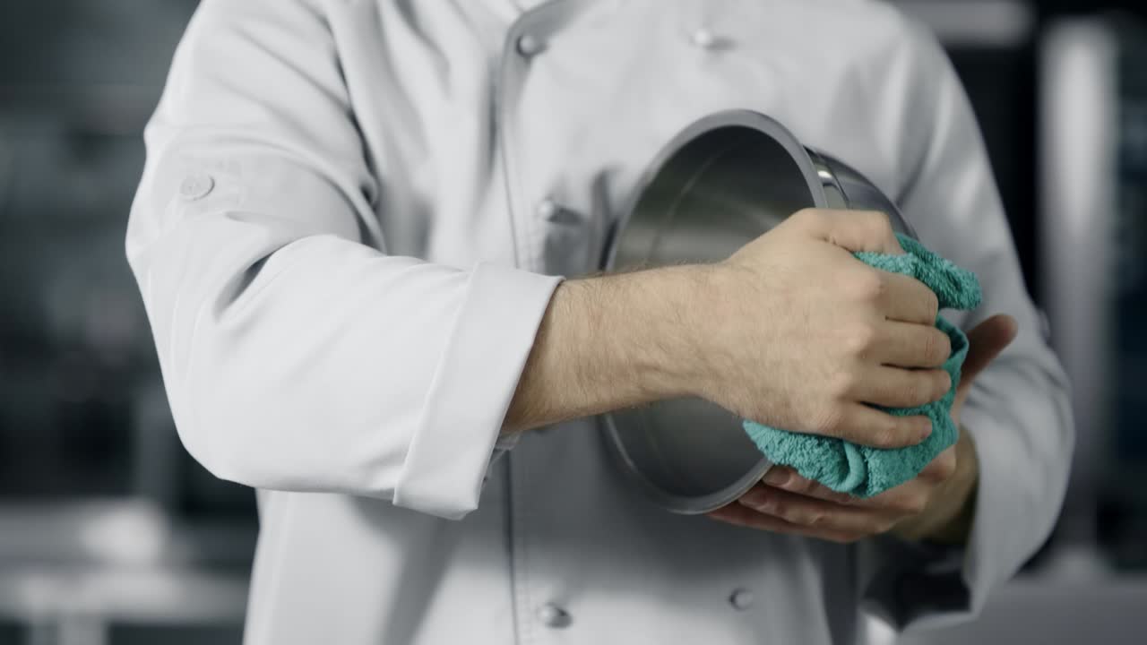 Chef man preparing to cook. Closeup man hands polishing bowl at kitchen.
