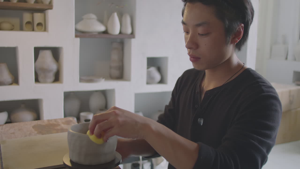 Asian Ceramist Wetting Clay on Pottery Wheel