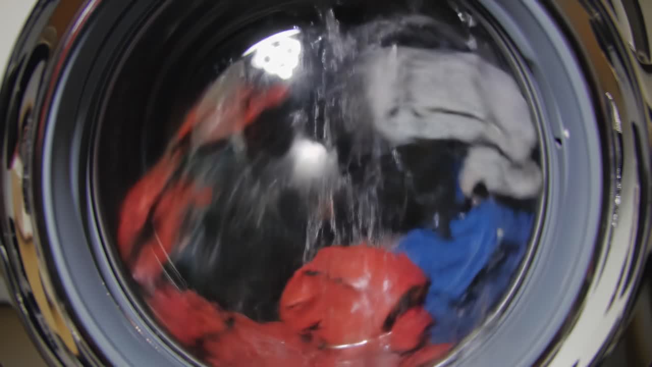 Washing Cycle Views: Capturing the Dynamic Movement of Clothes Inside a Washing Machine During a Spin Cycle with Water and Colorful Fabrics