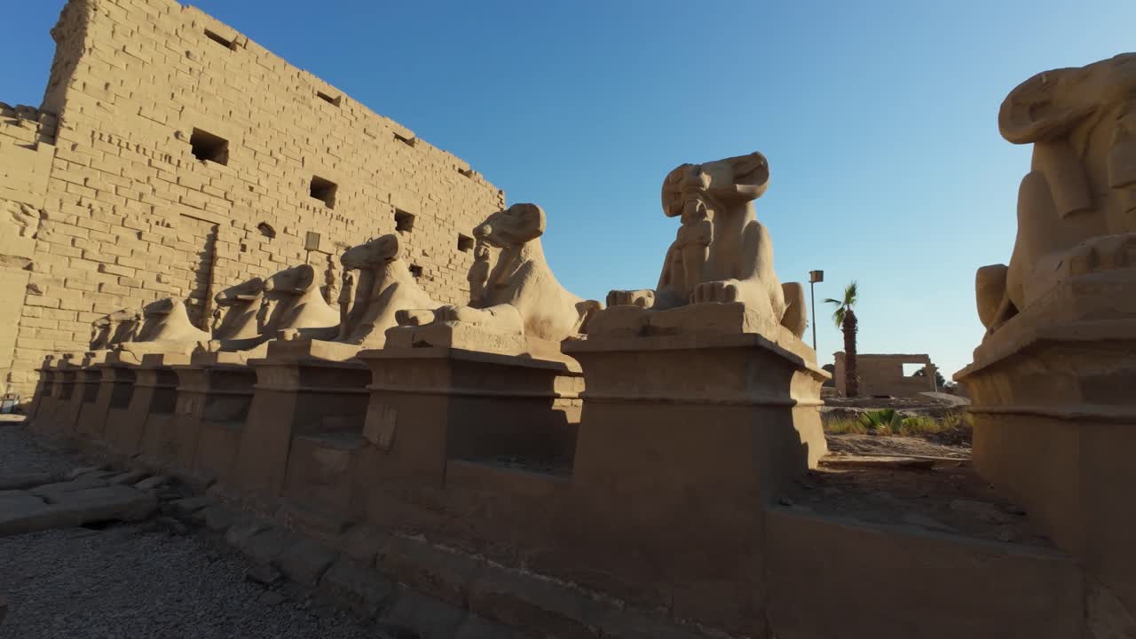 Row of ram-headed sphinxes under blue sky at Karnak Temple, Egypt