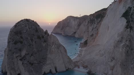 Aerial---Sunset-reveal-behind-tall-rock-in-Keri,-Zakynthos