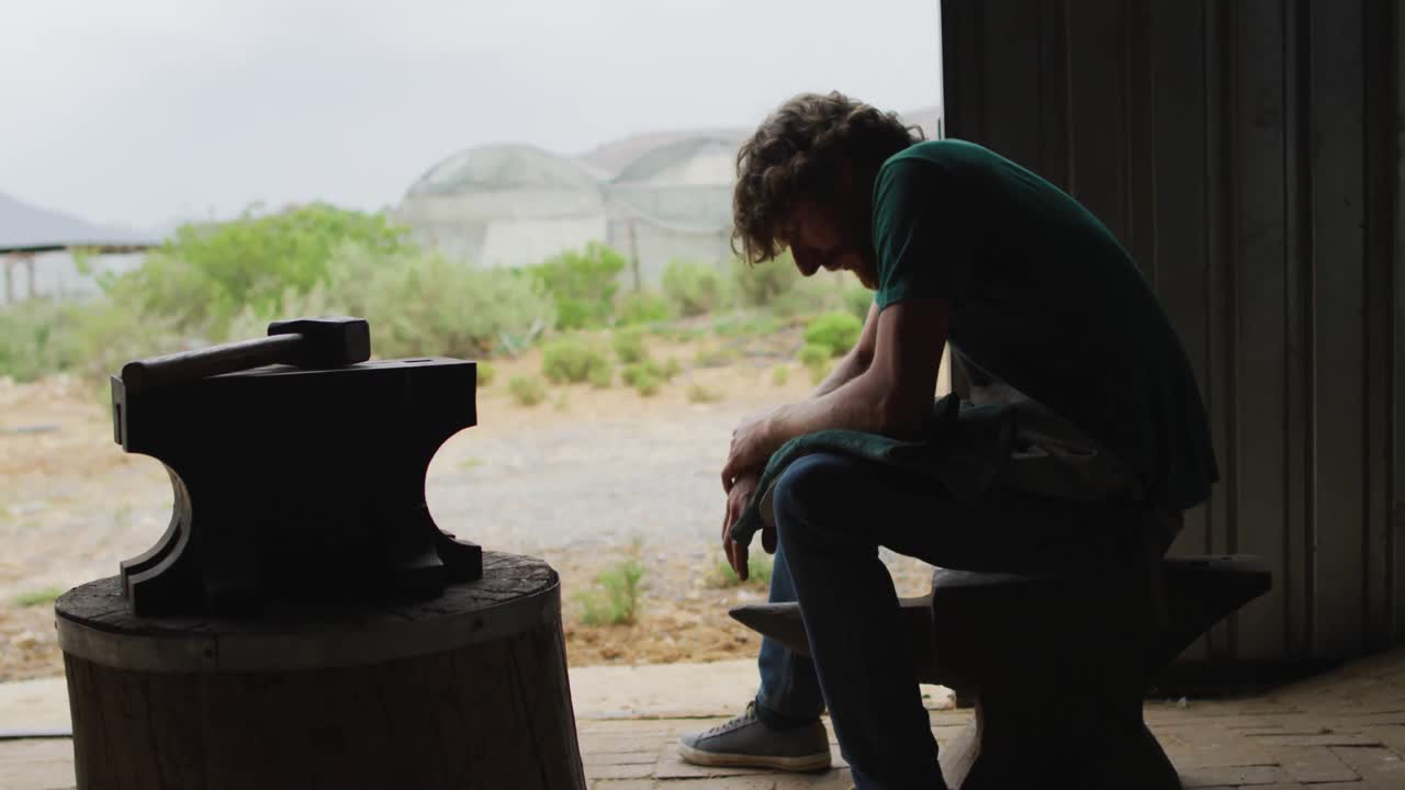 지친 백인 남성 도공이 작업장에서 휴식을 취하고 있습니다.