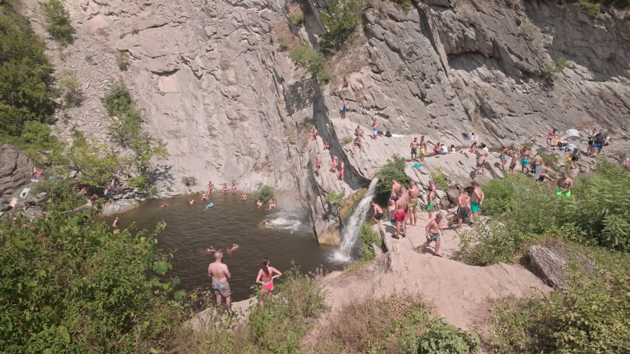 People swimming and enjoying a natural waterfall pool