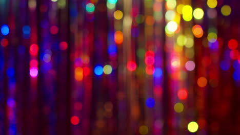 prise de vue d'un rideau de tinsel défocalisé dans une boîte de nuit ou une discothèque avec des lumières scintillantes réfléchies