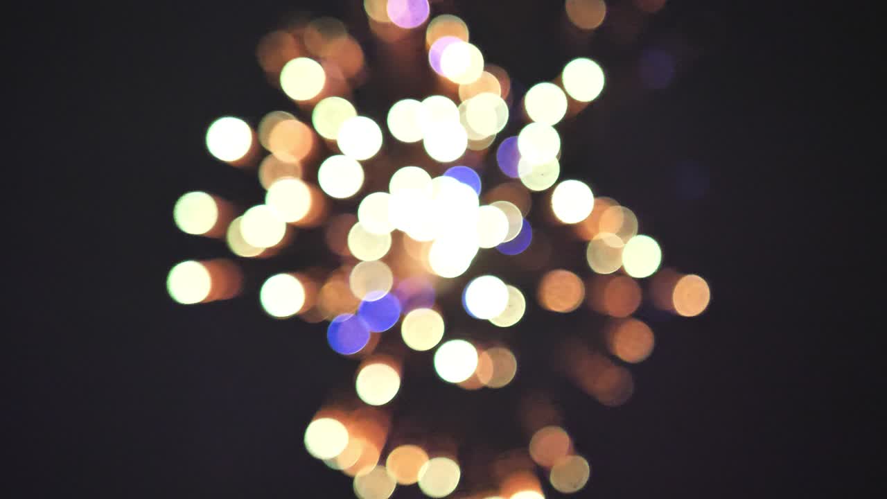 Slowmotion-optagelse af fyrværkeri, der eksploderer i luften og skaber farverige bokeh-bobler på den 4. juli