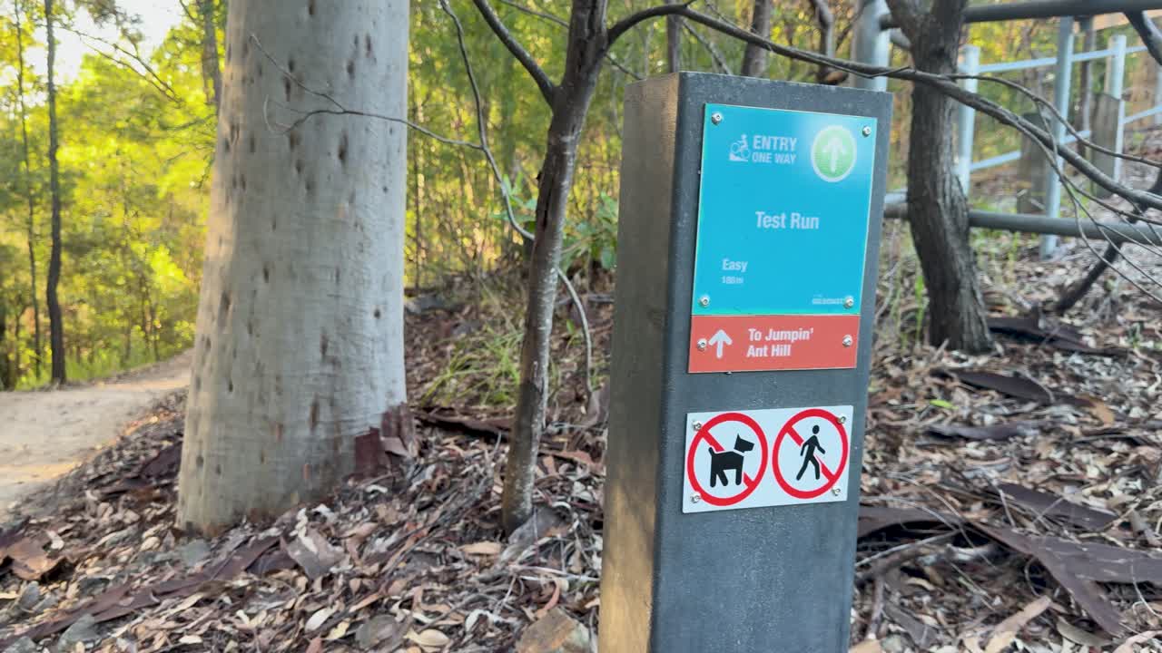 Inquadratura fissa di un cartello segnaletico su un sentiero per mountain bike all'interno della boscaglia di eucalipti australiana.