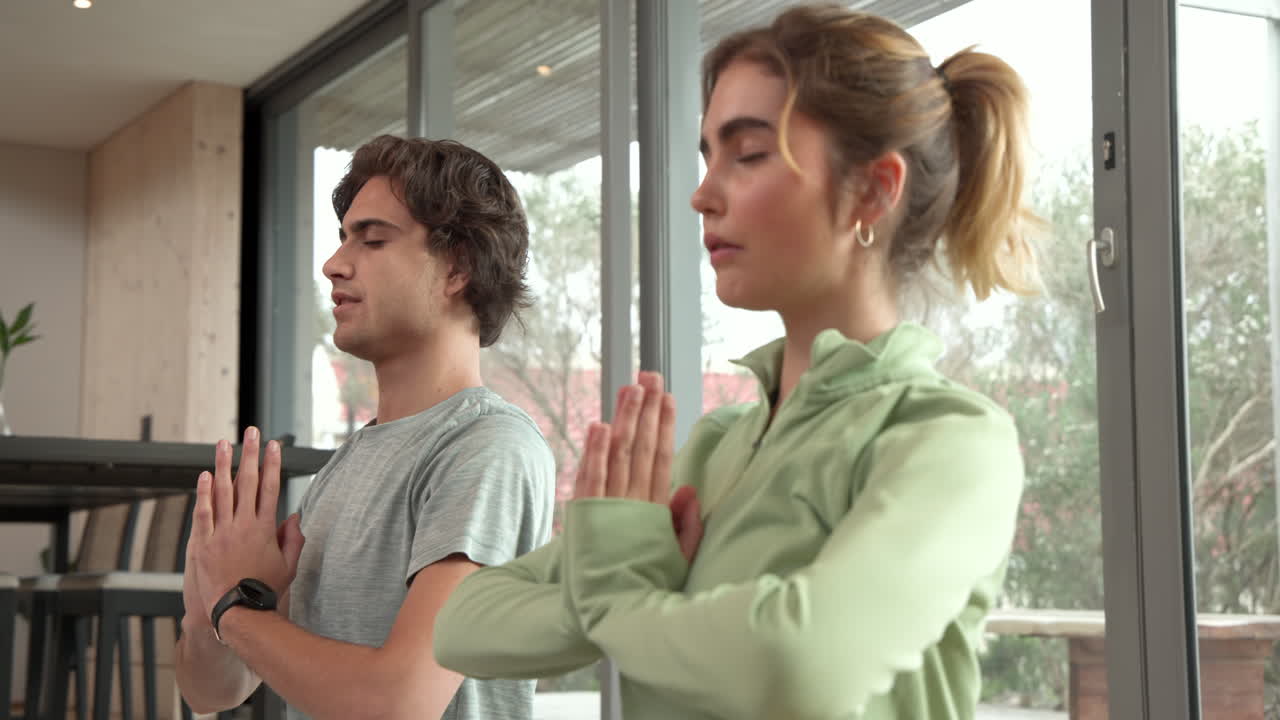 Practicing yoga at home, couple meditating with peaceful expressions and focus