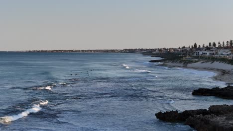 Aerial-view-of-surfers-in-the-line-up-waiting-for-their-next-wave-at-sunrise