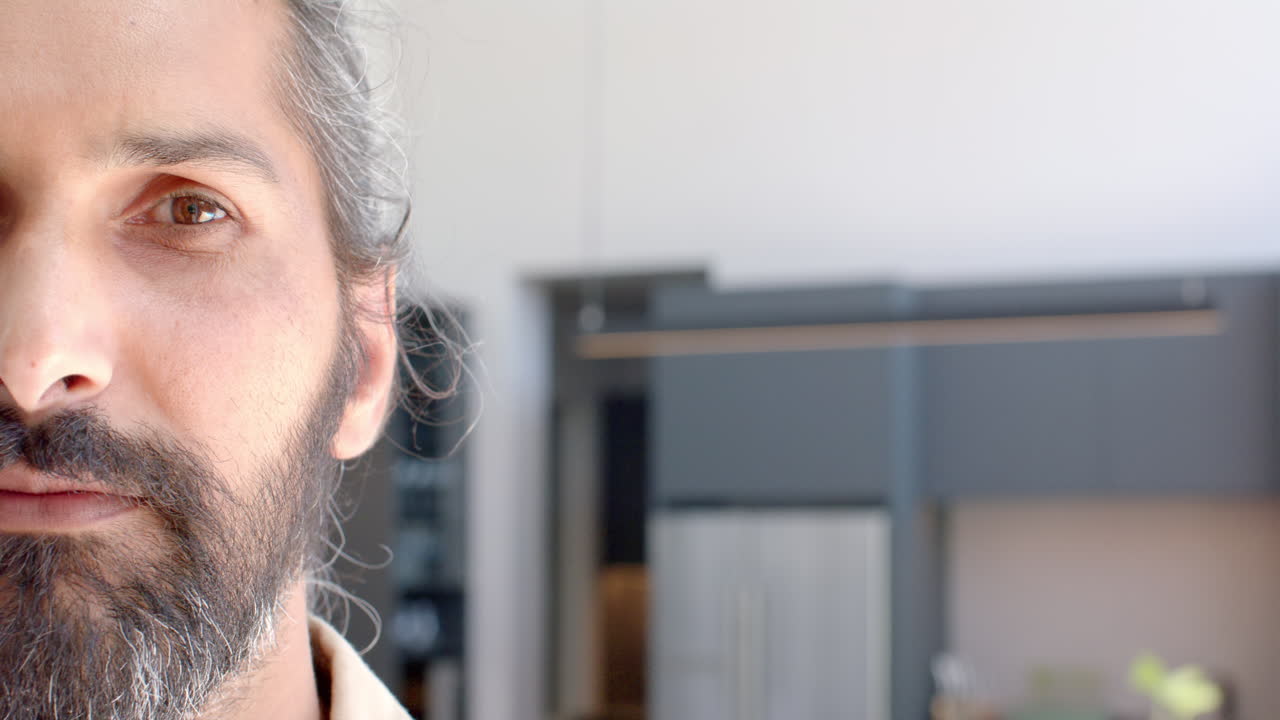 Close-up of man with beard in modern kitchen at home, looking serious