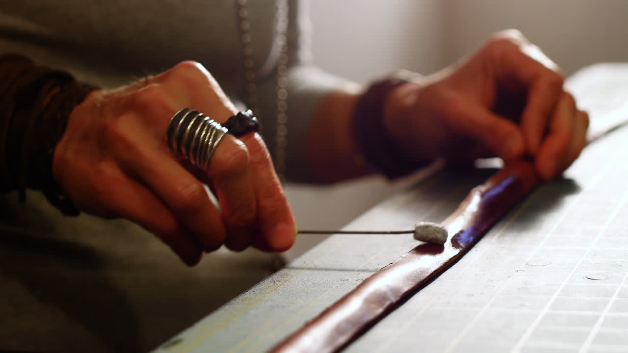 Mid-section of craftswoman preparing leather belt