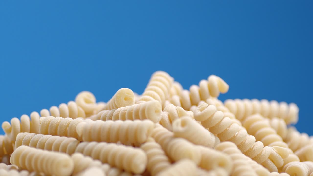 un montón de pasta de fusilli seco gira lentamente.