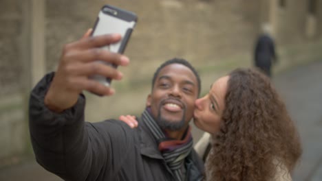 Frau-Küsst-Mann-Für-Selfie-Auf-Die-Wange