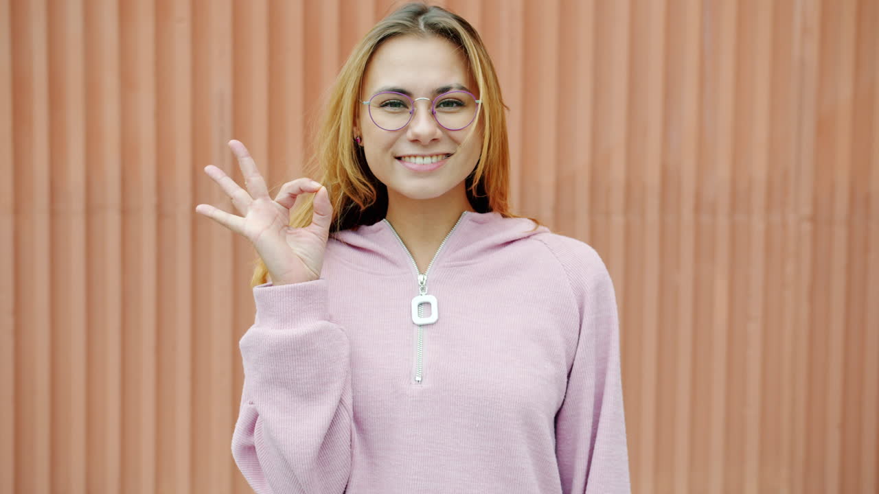 Young woman smiling and making an ok sign