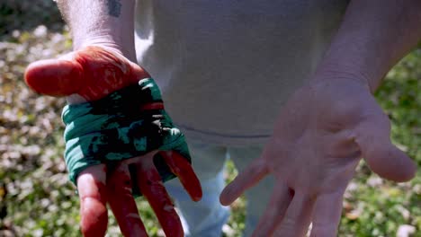 Hombre-Caucásico-Abre-Sus-Manos-Mostrando-Una-Mano-Ensangrentada-Con-Torniquete-Improvisado-De-Tela,-Cámara-Lenta