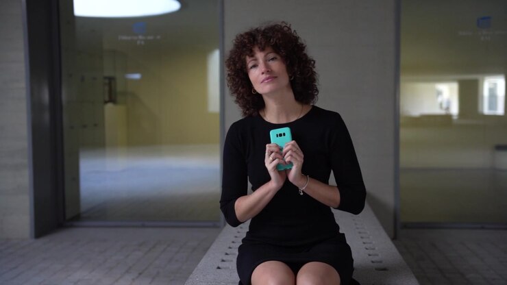 Una donna sicura di sé che interagisce attivamente con il suo smartphone in un ambiente spazioso, moderno ed elegante