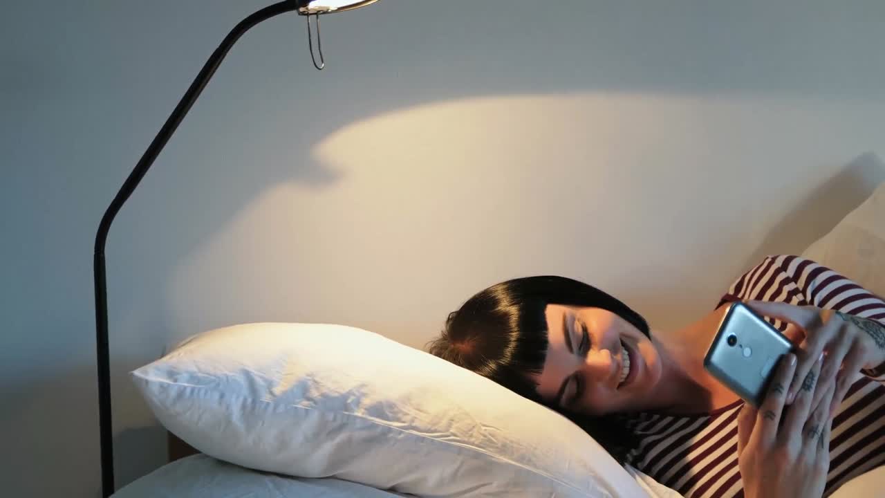 침실 4k에서 휴대 전화를 사용하는 여성