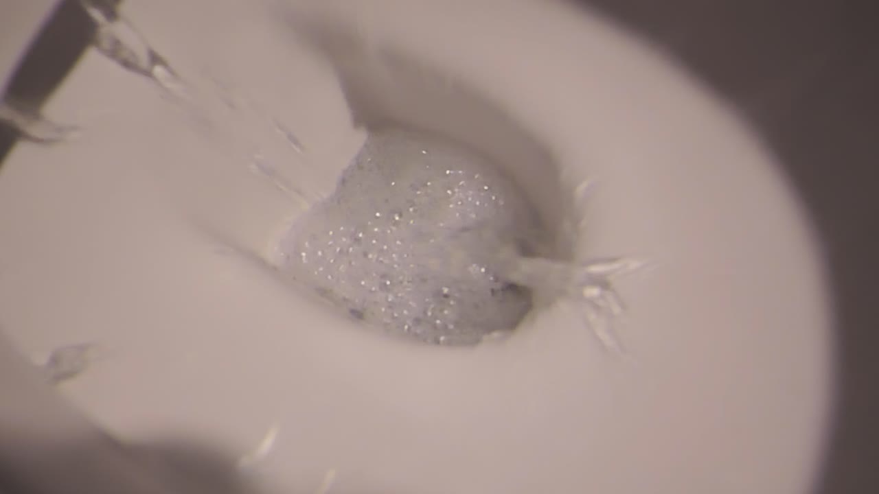 Close-up view of toilet flushing yellow residue - illustrating hygiene cleaning