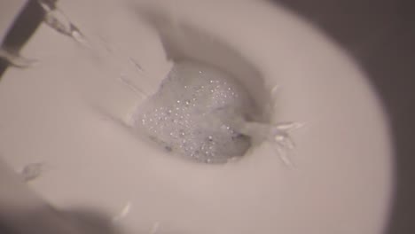 close-up view of toilet flushing yellow residue - illustrating hygiene cleaning