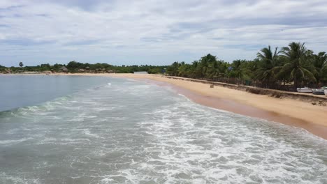 Aerial-flying-at-low-altitude-fast-above-ocean-and-waves-in-popular-surfing-destination-of-Arugam-Bay,-Sri-Lanka