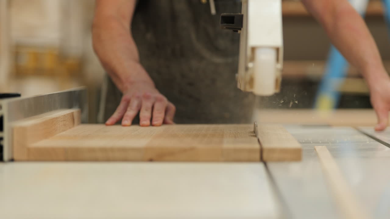A skilled craftsman is operating a table saw, cutting a wooden plank with precision in a well-lit workshop. Dust particles float in the air, highlighting the craftsmanship involved.
