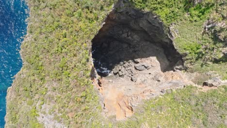 Toma-Aérea-De-Arriba-Hacia-Abajo-Que-Muestra-Pájaros-Volando-Sobre-Una-Cueva-En-El-Parque-Nacional-De-Cabo-Cabron-En-Verano